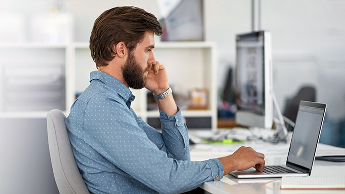 Businessman im blauen Hemd arbeitet mit MacBook